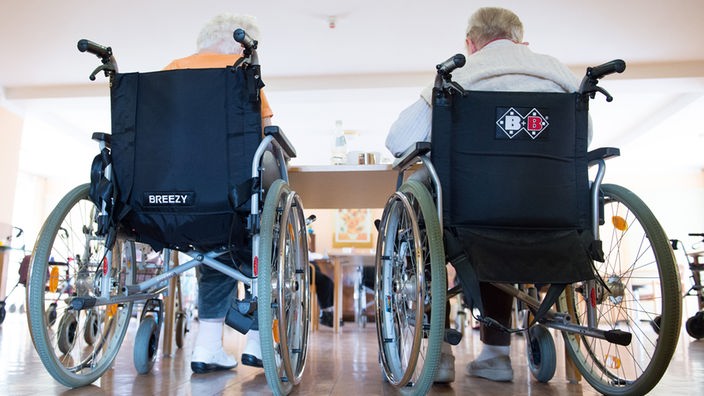 Zwei pflegebedürftige Frauen sitzen in einem Pflegeheim in ihren Rollstühlen