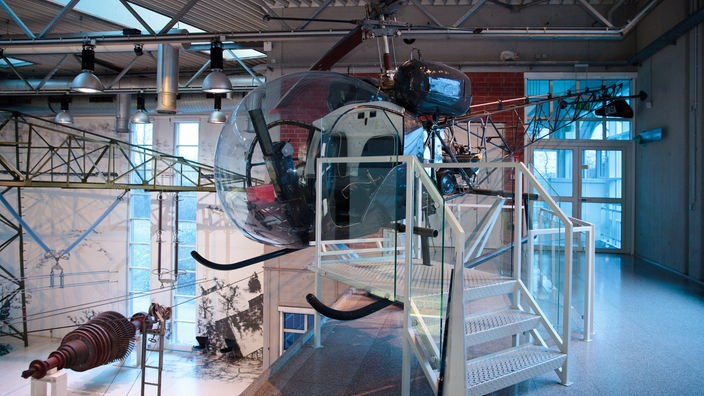 Ein Hubschrauber hängt unter der Decke in der DASA, davor steht eine kleine Treppe, damit Besucher:innen in den Hubschrauber hineinklettern können
