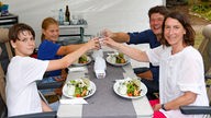 Familie Stamen stößt beim Abendessen im WDR 2 Zelt gemeinsam an