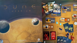 Die Spieleschachtel von "Dune: Imperium" mit Spielplan, Karten und Material auf einem Tisch