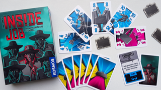 Die Spieleschachtel von Inside Job zeigt fünf Agenten in Trenchcoats. Sie liegt auf einem Tisch mit mehreren bunten Spielkarten mit Zahlenwerten.