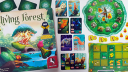 Die Spieleschachte von "Living Forest" mit Spielkarten, die verschiedene bunte Waldtiere zeigen, und Spielertableaus auf einem Tisch