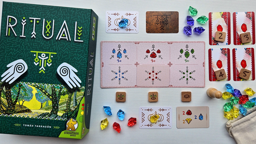 Die Spieleschachte von "Ritual" liegt neben dem Spielmaterial aus farbigen Karten und bunten Plastikedelsteinen auf einem Tisch