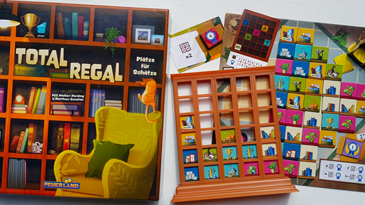 Die Spieleschachtel von "Total Regal", daneben der Wohnzimmer-Spielplan mit Sammlerstücken und ein halbgefülltes Regal aus braunem Plastik