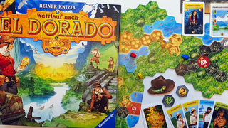 Die Spieleschachte von "Wettlauf nach El Dorado" auf einem Tisch, daneben der bunte Dschungelspielplan und Spielkarten, die verschiedene Expeditionsteilnehmer zeigen