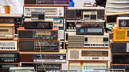 Eine Sammlung aufeinander gestapelter Radios verschiedener Jahrzehnte.