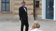 Er posiert im schwarzen Anzug mit Fliege bei den Bayreuther Festspiele am 14.07.2020 vor einer Straßenlaterne. Seine Partnerin, die Stargeigerin Lidia Baich, ist von hinten beim Fotografieren zu sehen.