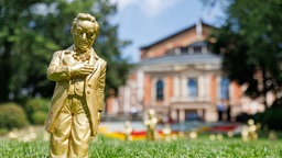 Goldfarbene Wagner-Figuren des Konzeptkünstler Ottmar Hörl stehen 25.07.2024 im Rahmen der Kunstinstallation "Verneigung" vor dem Festspielhaus vor dem Bayreuther Festsaal.