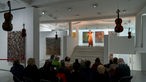70 Jahre Musik der Zeit: Die Violinistin Karin Hellqvist spielt, umgeben von 6 hängenden Geigen in der Galerie Karsten Greve