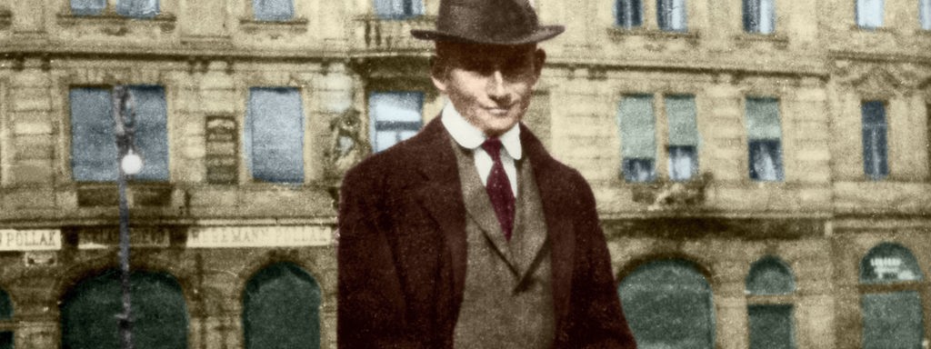 Kafka steht auf der Straße vor dem Wohnhaus, nachtraeglich koloriertt, vermutlich um 1910.