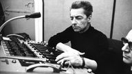 Herbert von Karajan schiebt mit konzentriertem Blick die Regler an einem Mischpult.