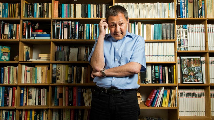 Der Autor und Blogger Akif Pirinçci steht vor einem Bücherregal