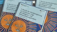 Das Cover des Berichts der Bundesregierung zur weltweiten Lage der Religions- und Weltanschauungsfreiheit in Berlin zeigt eine Sonne. 