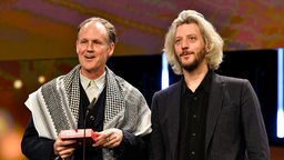 Ben Russell (links) mit einem sogenannten "Palästinensertuch" und Guillaume Cailleau auf der Bühen bei der Berlinale 2024.