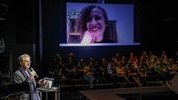 Carl Zuckmayer-Stipendium 2024: Das Bild von Carla Guimarães ist bei der Veranstaltung im Staatstheater Mainz auf einer großen Videoleinwand zu sehen.