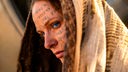 Filmszene aus dem zweiten Teil von "Dune": Eine Frau (Rebecca Ferguson) mit Schriftzeichen im Gesicht und einem Kopftuch.