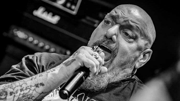 Schwarz-Weiß-Bild: Paul Di'Anno singt bei einem Konzert in ein Mikrofon.