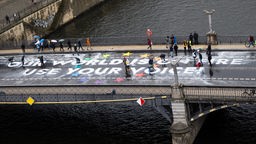 Klimaaktivisten der Bewegung Fridays for Future malen auf der Marschallbrücke den Schriftzug «Our world is on fire - use your voice!», um auf die Teilnahme an den Europawahlen am 9. Juni aufmerksam zu machen. 