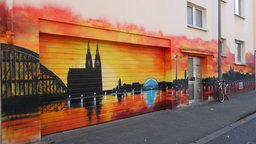 Panorama der Stadt bei untergehender Sonne mit Dom an einer Hausfassade mit Garage