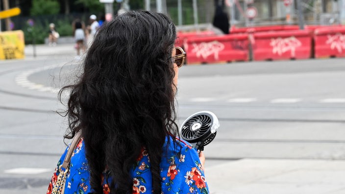 Aufgrund der extremen Hitze in Frankreich hält eine Passantin in Lyon einen Handventilator vor ihr Gesicht.