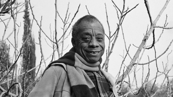 Schwarz-Weiß-Porträt von Schriftsteller James Baldwin vor Bäumen in Saint Paul de Vence an der Côte d'Azur.