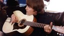 Lennon spielt auf der zwölfsaitigen Gitarre vom deutschen Hersteller Framus. Die Entstehung des Fotos wird auf um etwa 1960 geschätzt.