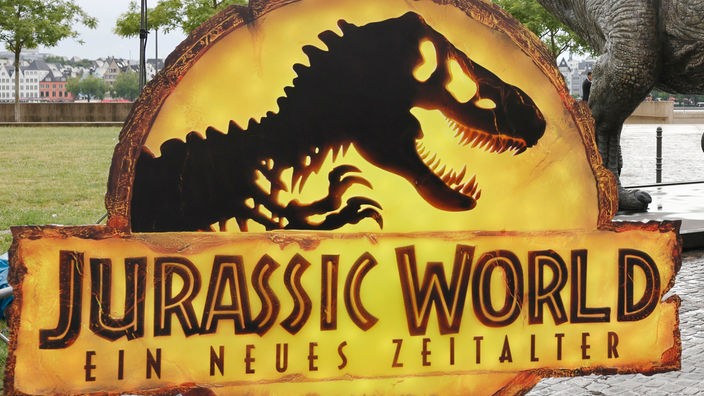  Das Logo von «Jurassic World» vor einer T-Rex Figur. 