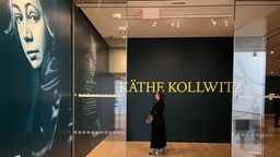 Eingangsbereich der Kollwitz-Ausstellung im New Yorker Museum of Modern Art mit einem großen Foto der Künstlerin, davor eine Besucherin.