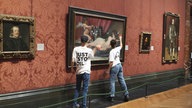 Zwei Demonstranten, die gegen den Klimawandel protestieren, zerschlagen eine schützende Glasscheibe, die ein berühmtes Ölgemälde von Diego Velázquez in der Londoner National Gallery abdeckt.