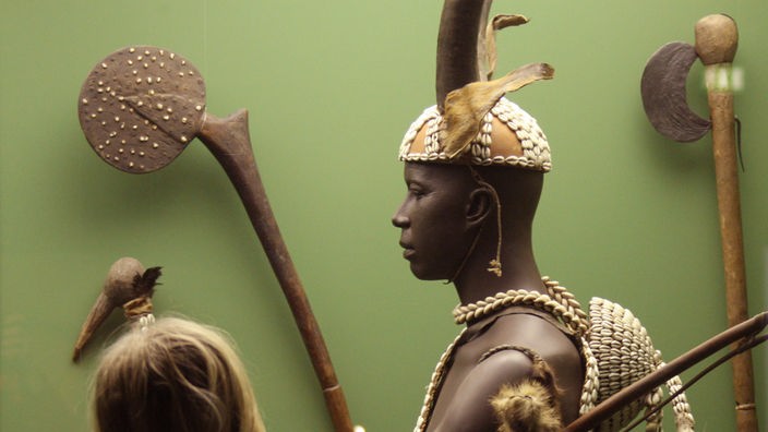 Ein Frau betrachtet einen jungen Moba-Mann in Tanztracht in der "Afrika"-Ausstellung im Grassi-Museum für Völkerkunde in Leipzig.