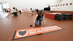 Caroline Schmidt, Klimaaktivistin der Letzten Generation, klebt im Museum Ludwig während einer Aktion ein Banner mit der Aufschrift «Letzte Generation vor den Kipppunkten» auf den Boden.