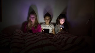 Drei Mädchen schauen gebannt auf ihre elektronischen Geräte