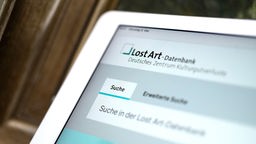 Ein Tablet, auf dem in einem Browser der Internet-Auftritt der Lost Art-Datenbank geöffnet ist, in der internationale Such- und Fundmeldungen von NS-Raubkunst veröffentlicht werden.
