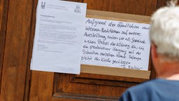 An der Eingangstür zur Nürnberger Kirche St. Egidien hängt eine Pressemitteilung so wie ein handgeschriebener Zettel zur vorübergehenden Schließung der Ausstellung "Jesus liebt".