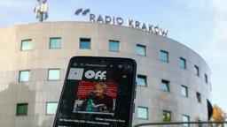 Gebäude mit Schriftzug des Jugendsenders Off Radio Krakau und Internetseite auf einem Handy