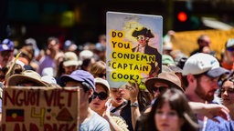 Proteste zum Nationalfeiertag in Australien: Ein Demonstrant hält ein Plakat, das sich auf den Entdecker Kapitän James Cook bezieht.