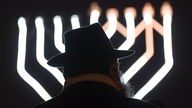 Rabbiner Zalman Gurevitch steht zum Auftakt des Lichterfestes im Dunkeln vor einer Lichtinstallation.