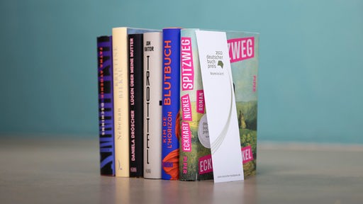 Bücher der Shortlist des Deutschen Buchpreises 2022 lehnen aufrecht aneinander