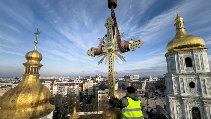 in Höhenarbeiter installiert ein restauriertes Kreuz auf einer Kuppel der Sophienkathedrale. Die zum UNESCO-Weltkulturerbe zählende Sophienkathedrale mit ihrer goldenen Kuppel im Herzen von Kiew wurde im 11. Jahrhundert erbaut. 