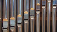 Symbolbild: Eine Reihe silberner Orgelpfeifen.