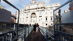 Menschen laufen auf dem neuen Steg im Trevi-Brunnen. 