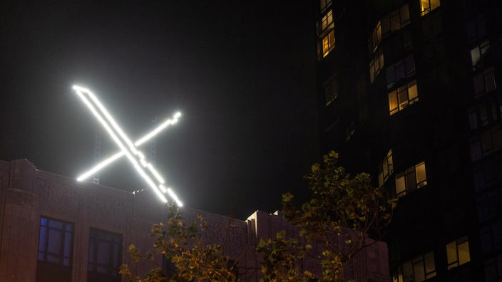 Das beleuchtete "X" Logo bei Dunkelheit auf dem Dach des Unterhmens in San Francisco.