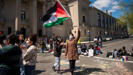 Eine pro-palästinensische Demonstrantin steht an einer Straßenkreuzung an der Yale University in New Haven und schwenkt eine palästinensische Flagge.