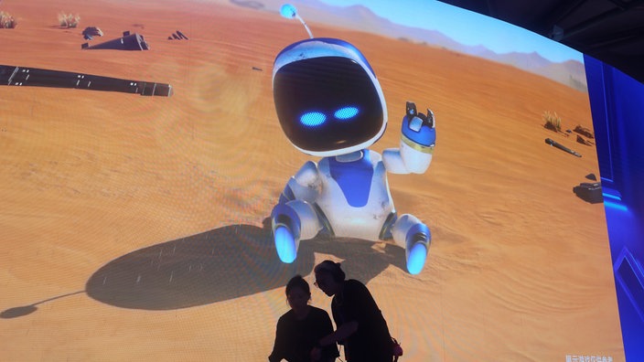 Touristen probieren vor einer großen Videowand das Videospiel "Astro Bot" der Sony PS5-Ausstellungsfläche der 2024 ChinaJoy in Shanghai aus.