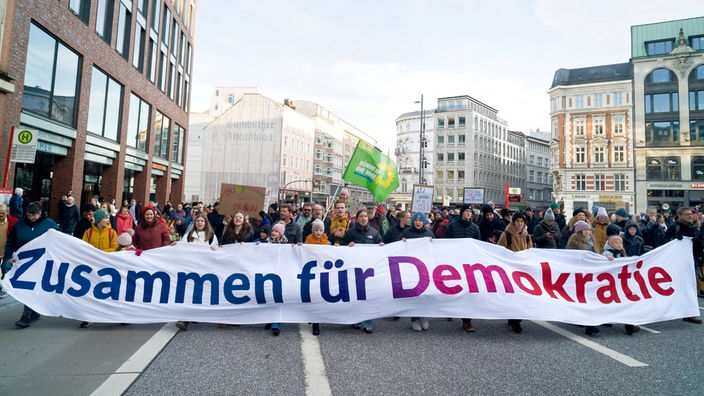 Demonstrierende bei einer Demo gegen Rechts in Hamburg halten ein Banner mit der Aufschrift: Zusammen für Demokratie! 