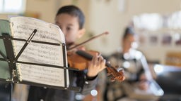 Ein Junge spielt Geige während des Musikunterrichts
