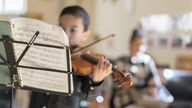 Ein Junge spielt Geige während des Musikunterrichts