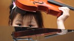 Ein Mädchen hält eine Geige über seinen Kopf