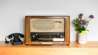 Ein altes Radiogerät mit einem Bakelit-Telefon und einer Blumenvase