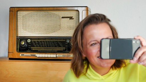 Eine Frau macht ein Selfie vor ihrem alten Radio